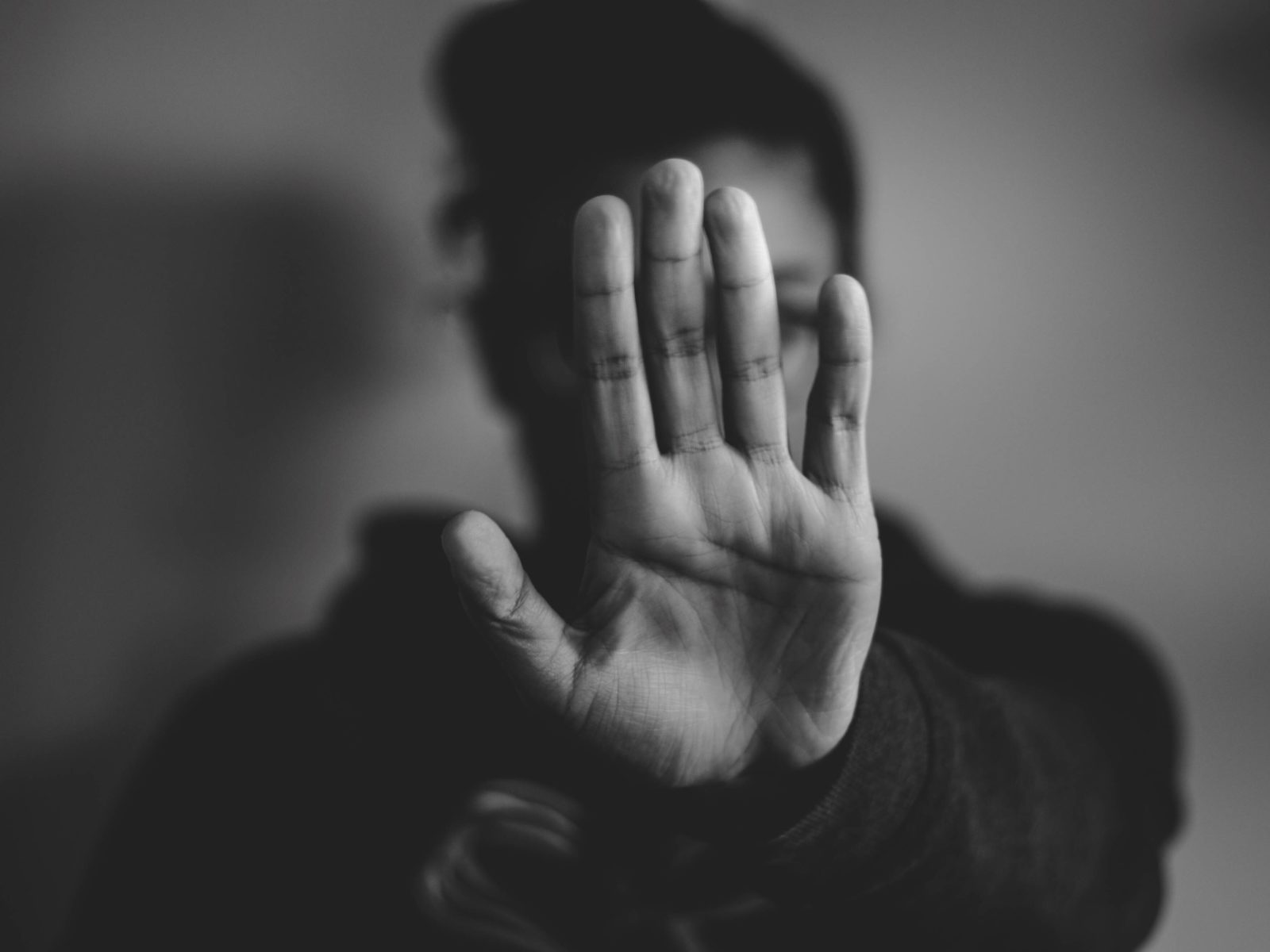 eine Person hällt schützend die Hand vor ihr Gesicht